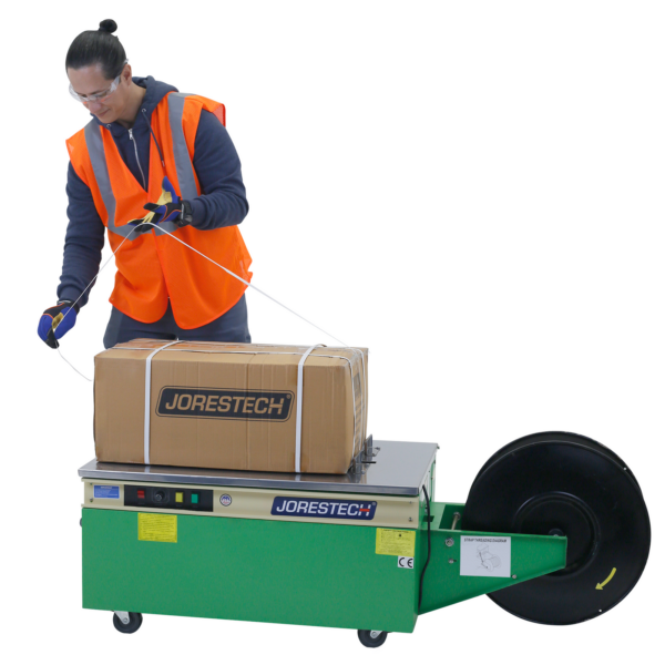 Hombre usando la enfajadora de polietileno de perfil bajo JORESTECH® para asegurar y empaquetar una caja para envío