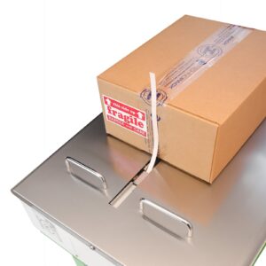 Primer plano del área de trabajo de acero inoxidable de la máquina de flejado. La cinta sale del canal de suministro y una caja de cartón está colocada para ser flejada