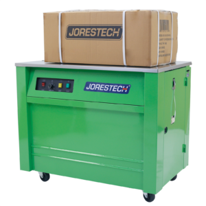 La máquina de flejado semiautomática de polietileno JORES TECHNOLOGIES® verde con una caja de cartón grande colocada sobre la máquina y 4 flejes de polietileno asegurando la caja alrededor