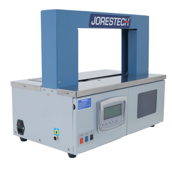 Vista diagonal de una máquina de flejado de sobremesa JORES TECHNOLOGIES® ® en gris y azul para bandas de papel y plástico sobre fondo blanco.