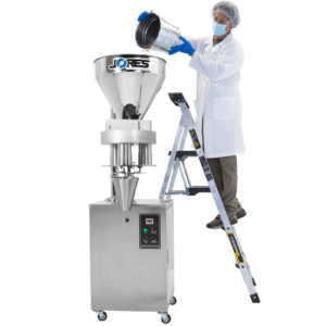Trabajador de pie sobre una escalera vertiendo un cubo lleno de frijoles en la tolva de acero inoxidable de la llenadora volumétrica semiautomática JORES TECHNOLOGIES® de 1000 ml