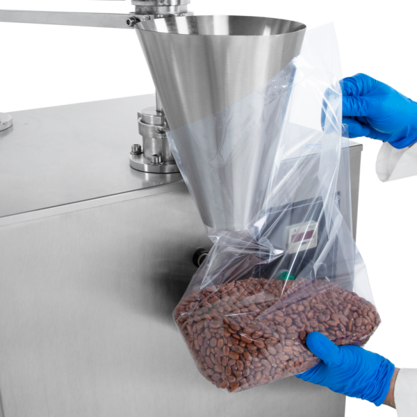 Manos de un trabajador sosteniendo una bolsa de plástico transparente debajo del cono de dispensación de la llenadora volumétrica semiautomática. La máquina de llenado libera 2000 ml de frijoles rojos de flujo libre con precisión