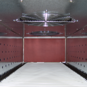 Detalle del interior del horno de termorretracción mostrando la cámara de calentamiento, paredes perforadas de acero inoxidable, rejillas de acero inoxidable para los ventiladores de calentamiento, un transportador de rodillos y la cortina de salida del túnel de calor de la túnel envolvedora Jorestech de 20 x 12 pulgadas
