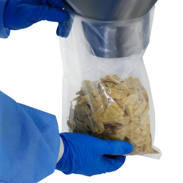 Vista en primer plano de una bolsa transparente con chips de tortilla en su interior. Un operador con guantes azules sostiene la bolsa, que acaba de ser llenada con una pesadora lineal comercial de cabeza única JORES TECHNOLOGIES®