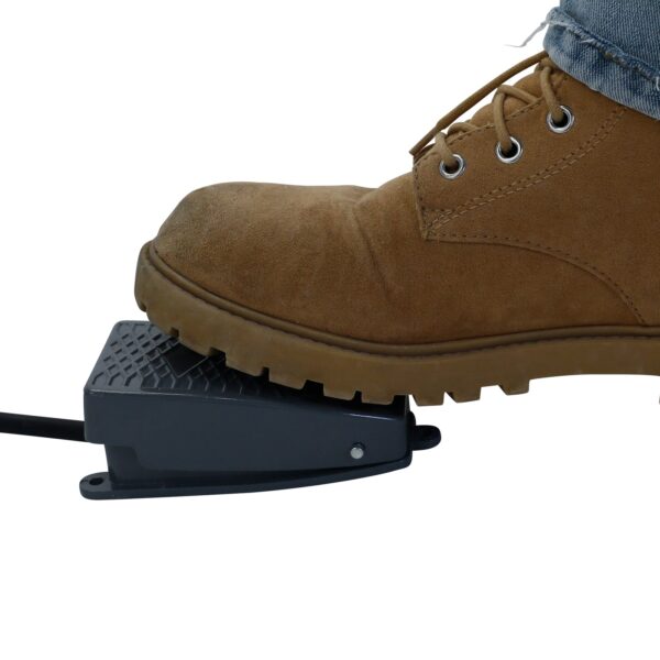 Primer plano del pedal gris arco perteneciente a una pesadora lineal JORES TECHNOLOGIES®. Se puede ver a una persona con botas marrones y jeans presionando el pedal para indicar a la máquina que inicie un ciclo de dispensado.