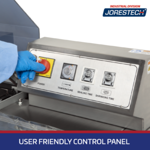 Primer plano del panel de control de acero inoxidable en una máquina de envoltura retráctil tipo cámara JORES TECHNOLOGIES®. Una mano con guante azul está accionando el interruptor ON / OFF. El panel de control muestra perillas giratorias para el control de temperatura, el tiempo de sellado y el tiempo de contracción. Una banda azul en la parte inferior con letras blancas dice User Friendly Control Panel.