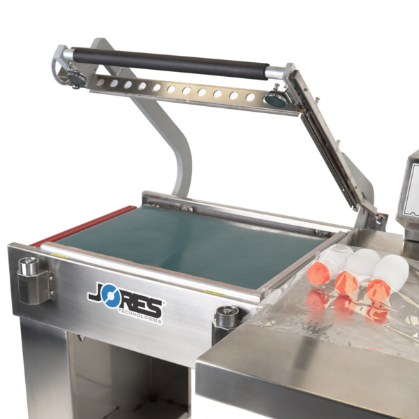 Selladora térmica semiautomática en L de acero inoxidable con cinta transportadora para empaquetar paquetes de envases de plástico de tamaño mediano.