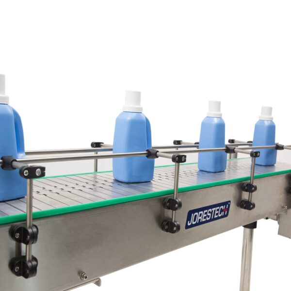 Primer plano de la cadena del transportador motorizado de acero inoxidable mientras se transportan varias botellas grandes de plástico azules y blancas