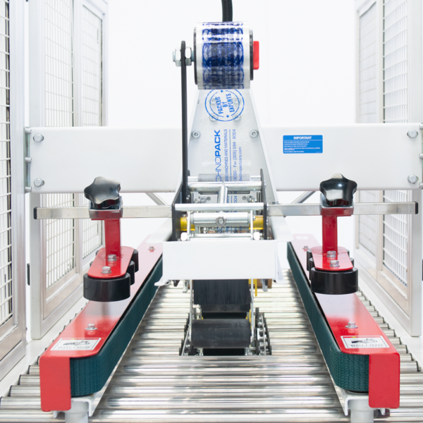 primer plano de la máquina selladora de cajas con barras laterales de tracción rojas y bandas de tracción verdes