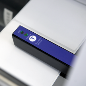 primer plano del sensor de etiquetas azul en aplicador de etiquetas semiautomático