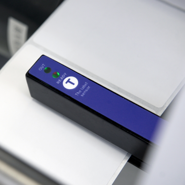 primer plano del sensor de etiquetas azul en aplicador de etiquetas semiautomático