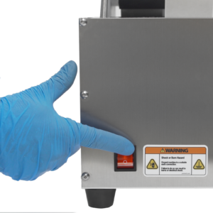 operador con guantes azules presionando un interruptor rojo para encender la aplicadora de etiquetas semiautomática JORES TECHNOLOGIES®