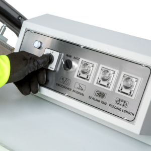 Primer plano del panel de control del sellador tipo L de la máquina. Una persona está girando una perilla para encender la máquina.