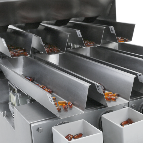 Primer plano de una pesadora lineal de cuatro cabezales JORES TECHNOLOGIES® midiendo y dispensando cápsulas de gel