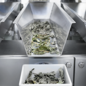 Primer plano de una pesadora lineal JORES TECHNOLOGIES® de cuatro cabezales midiendo y dosificando hierbas o especias