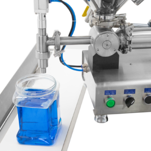 Primer plano de la boquilla antigoteo de una llenadora de pasta de sobremesa JORES TECHNOLOGIES® con tolva calentada y un recipiente transparente con líquido azul después de haber sido llenado