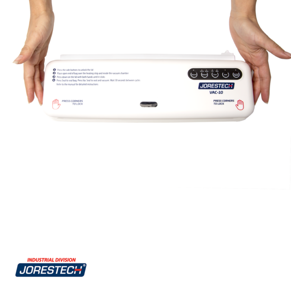Máquina de sellado al vacío blanca JORES TECHNOLOGIES® con cortador sobre un fondo blanco. Las manos de una persona están tocando los dos botones de liberación laterales en la tapa de vacío para abrirla.
