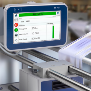 La impresora de transferencia térmica LINX TT750 para formato estándar, instalada en un soporte mientras imprime sobre una película en movimiento