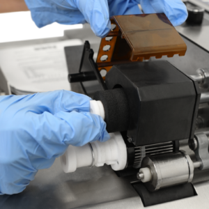 Primer plano que muestra la mano de una persona insertando un rodillo de tinta caliente negro en el codificador de rodillo de tinta caliente. También muestra el portatipos en su lugar