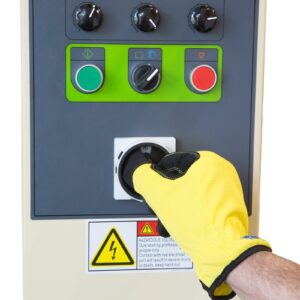 Primer plano detallado del panel de control de una envolvedora de palets con film estirable. Una mano con un guante de seguridad amarillo está ajustando uno de los mandos de control.