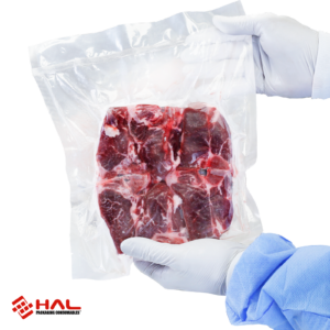 Manos de una persona sosteniendo una bolsa sellada al vacío con un gran trozo de carne cruda en su interior. La bolsa de vacío fue sellada y aspirada con la envasadora al vacío comercial de doble sellado JORES TECHNOLOGIES®