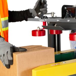 operador con guantes grises y negros introduciendo una caja marrón en una máquina cerradora de cajas como parte del proceso de embalaje