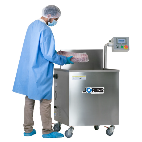 Persona con ropa protectora desechable retirando una parrilla de costillas con film termorretráctil del tanque de una máquina termorretráctil de agua caliente tipo inmersión semiautomática JORES TECHNOLOGIES®