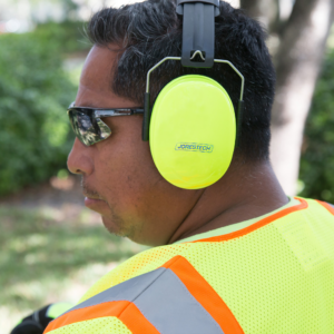 Un trabajador con orejeras protectoras sobre gafas de sol en un entorno al aire libre