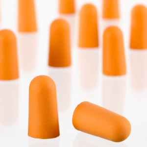 Primer plano que muestra en detalle la suave espuma naranja de 2 tapones para los oídos. Se pueden ver muchos tapones para los oídos adicionales al fondo.