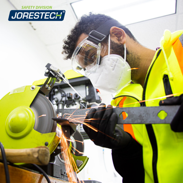 Un mecánico que lleva gafas de seguridad JORESTECH mientras opera una máquina herramienta eléctrica