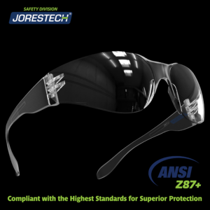 Unas gafas de seguridad transparentes antivaho JORESTECH para protección de alto impacto sobre fondo negro. Letras brillantes en verde y azul dicen: Cumple con ANSI Z87+, con los más altos estándares para una protección superior.