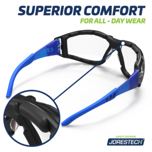 Vista de la parte posterior de las gafas de seguridad JORESTECH antiempañantes azules y transparentes convertibles en goggles con patillas desmontables y banda elástica para la cabeza. Se muestra un primer plano de la junta de espuma en un círculo y el texto dice comodidad superior para uso durante todo el día.