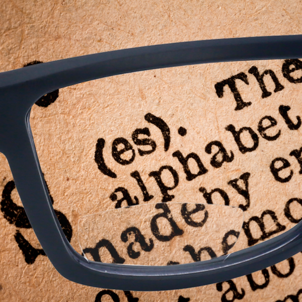 Las gafas de lectura de seguridad bifocales Jorestech colocadas sobre un texto. Las letras se pueden ver ampliadas en la parte inferior de la lente