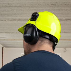 Trabajador que lleva un casco de seguridad tipo gorra con ranuras y protección auditiva para el trabajo