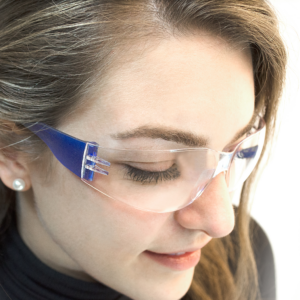 Una mujer usando las gafas de seguridad JORESTECH transparentes y azules, conformes con ANSI, para alta protección contra impactos