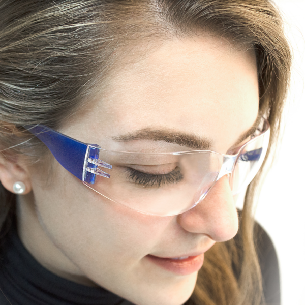 Una mujer usando las gafas de seguridad JORESTECH transparentes y azules, conformes con ANSI, para alta protección contra impactos