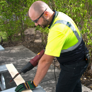 Trabajador con tapones para los oídos JORESTECH mientras opera una herramienta eléctrica ruidosa para preparar material de construcción.