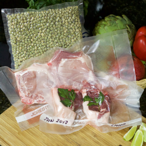 Muestra un grupo de bolsas llenas, envasadas al vacío y selladas con diferentes productos alimenticios en un entorno de cocina.