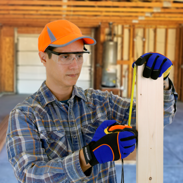 Hombre en un garaje con guantes de seguridad y las gafas de seguridad rectangulares con montura y protectores laterales para protección ocular contra impactos altos, midiendo un trozo de madera que usa en un proyecto de bricolaje