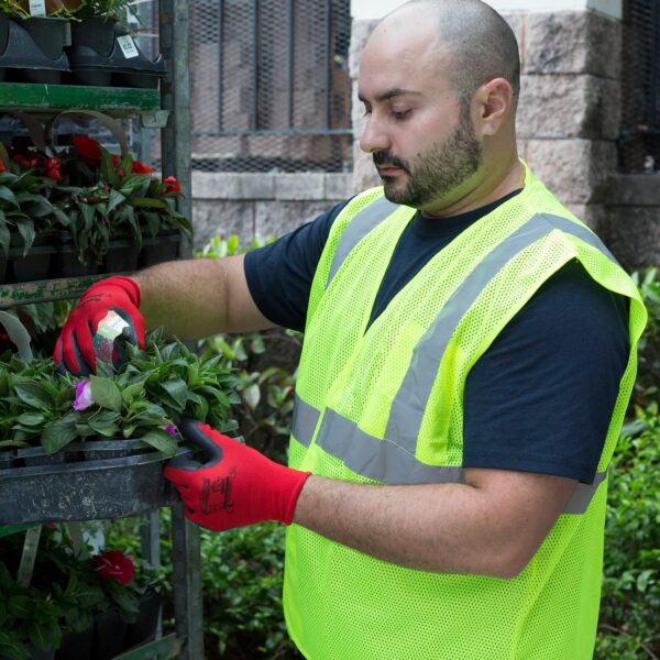 Jardinero usando el chaleco de seguridad color lima mientras está en un vivero organizando las plantas