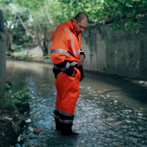 Trabajador usando el conjunto de lluvia de seguridad Hi Vis naranja con pantalón y chaqueta