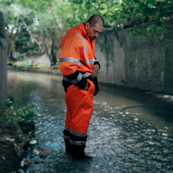 Trabajador usando el conjunto de lluvia de seguridad Hi Vis naranja con pantalón y chaqueta