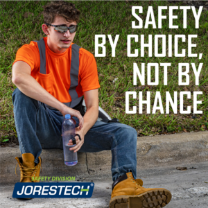 Trabajador que lleva una camisa de seguridad naranja y negra JORESTECH. Está sentado en el suelo con una botella de agua refrescándose en una obra de construcción. Un texto dice: la seguridad por elección, no por casualidad.