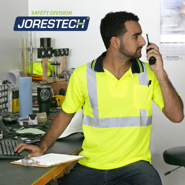 Un trabajador lleva una camiseta polo amarilla mientras trabaja en un taller.