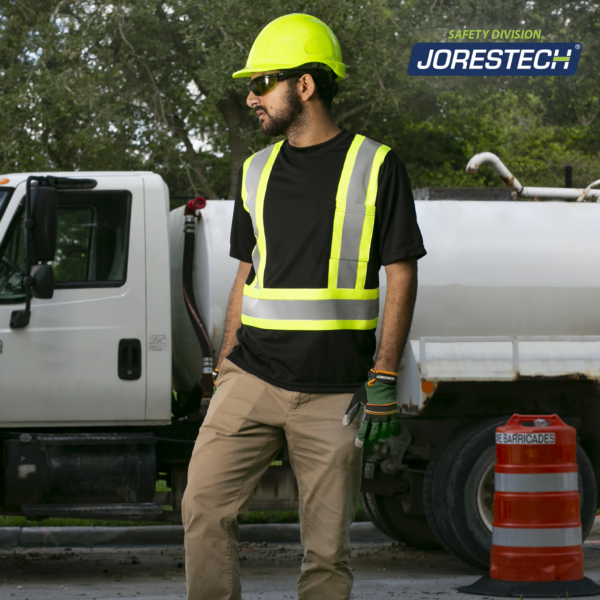Un trabajador que lleva la camiseta de seguridad JORESTECH de manga corta, alta visibilidad, reflectante, bicolor, negra y amarilla, con bolsillo, mientras conduce un camión de agua potable