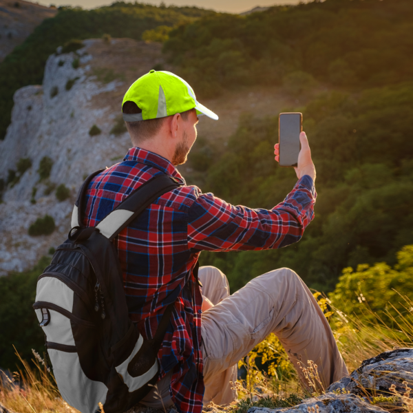 Una persona haciendo senderismo en una montaña con la gorra de seguridad de alta visibilidad JORESTECH con franjas reflectantes para su protección y aumentar la visibilidad