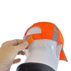 Primer plano de una mano tirando del cierre de gancho y bucle para ajustar el ancho de la gorra de seguridad naranja Hi-Vis JORESTECH