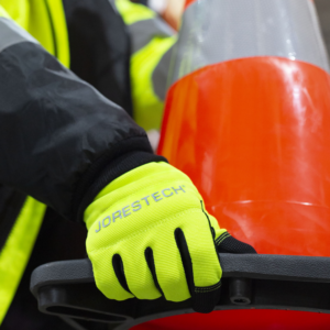 Persona que lleva los guantes de seguridad multipropósito de alta visibilidad mientras transporta un cono de calle