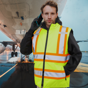 Un hombre con chaleco reflectante amarillo para protección invernal en la pista de un aeropuerto
