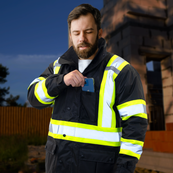Trabajador que lleva la chaqueta negra aislante de alta visibilidad con franjas reflectantes y amarillas